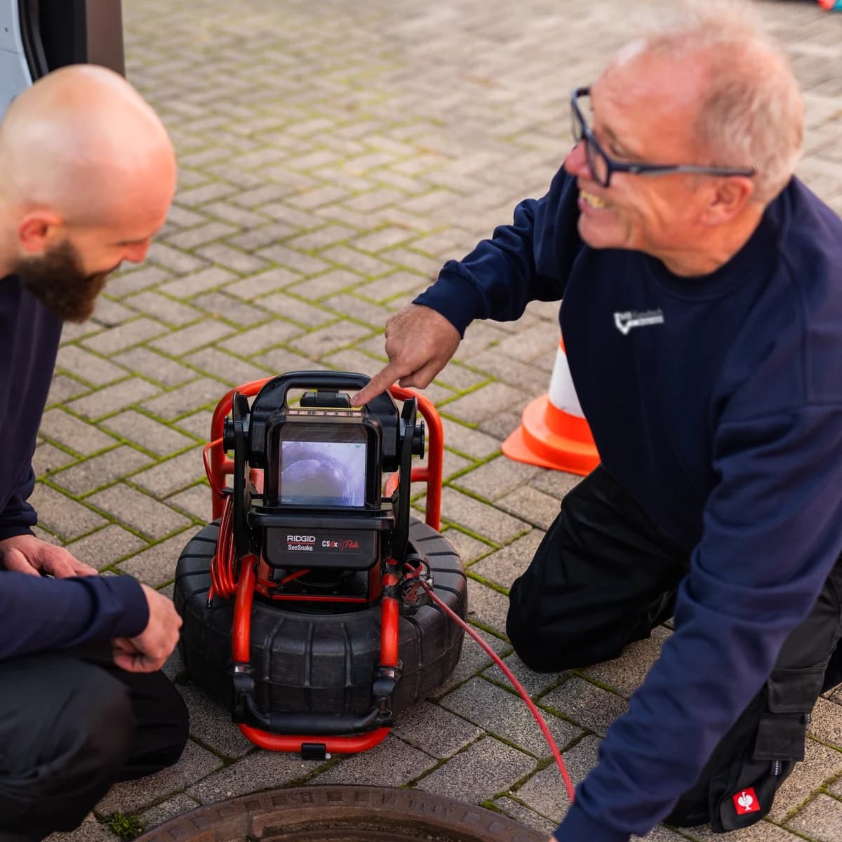 Zwei Techniker der MB Kanaltech München GmbH werten das Kamerabild am Schacht aus
