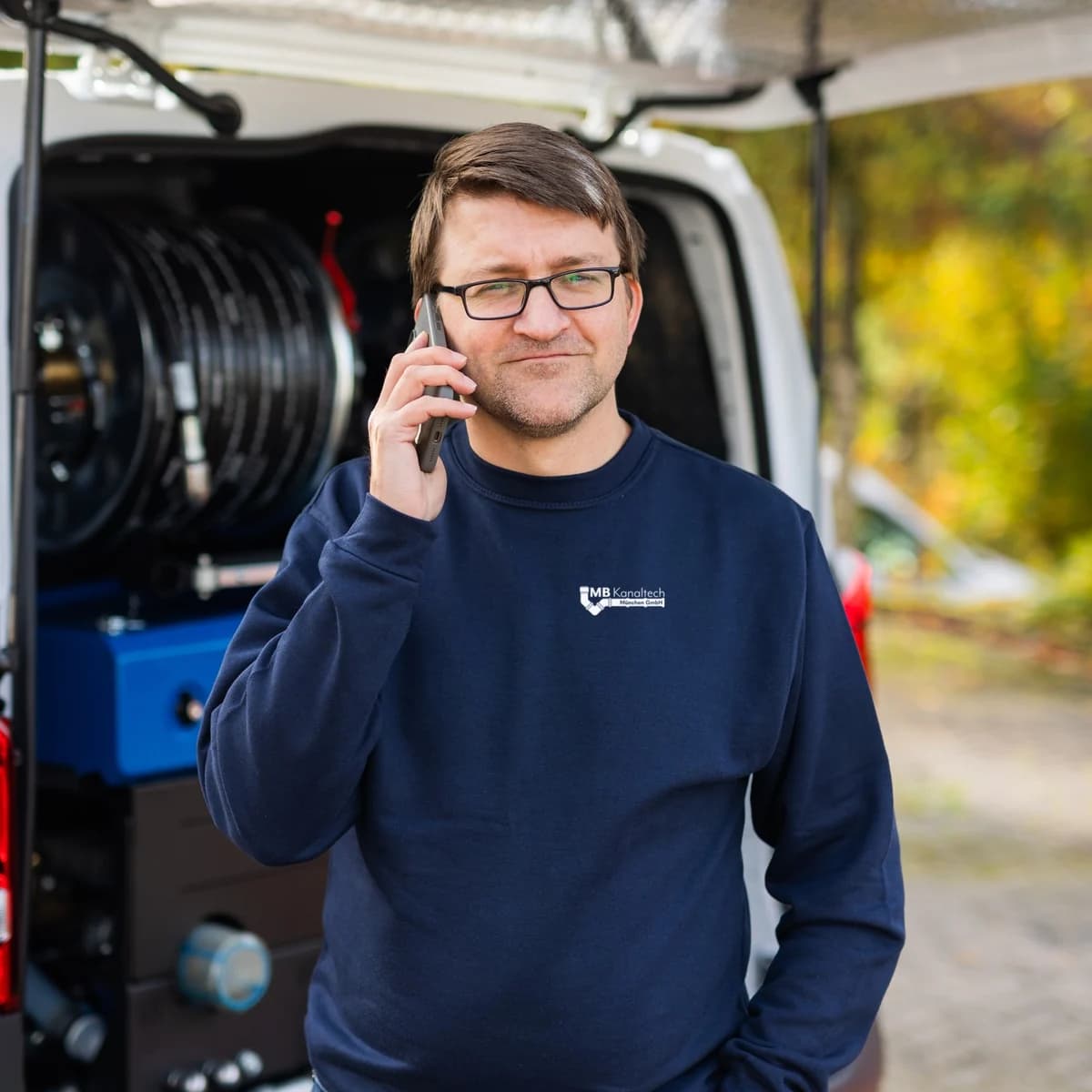 Techniker der MB Kanaltech München GmbH telefoniert am Einsatzfahrzeug
